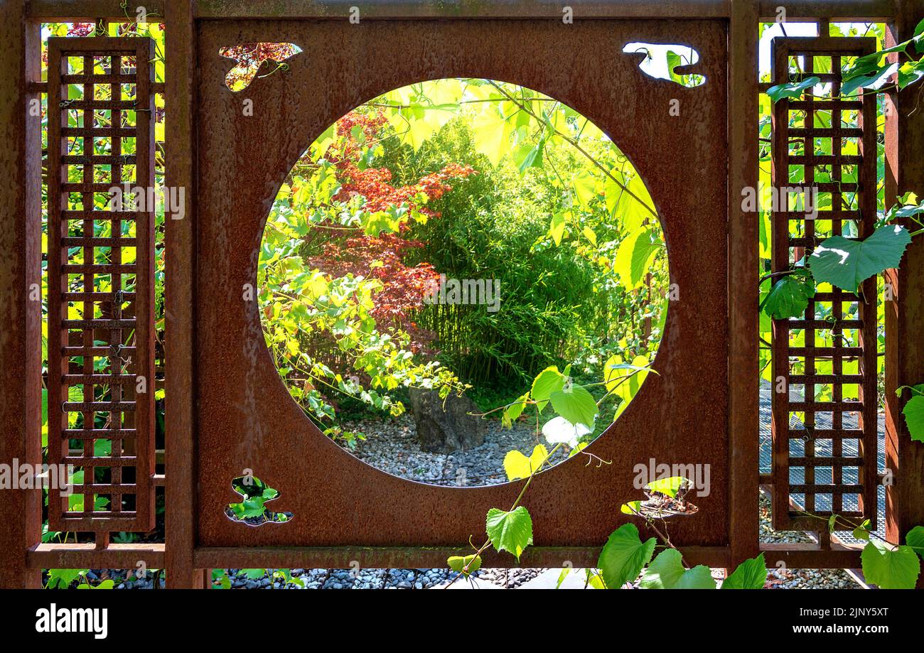 rusty iron divider with a circular window in a sunny garden Stock Photo