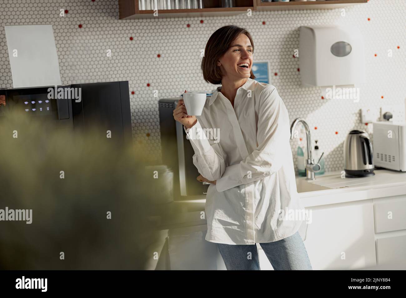 Smiling business woman in casual clothes drinking coffee in office