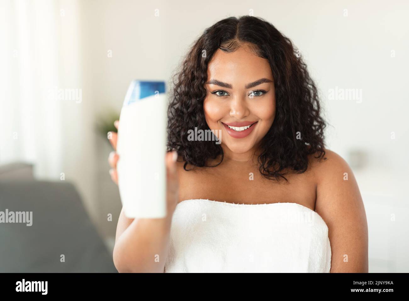 Happy african american oversize woman showing shower gel bottle ...