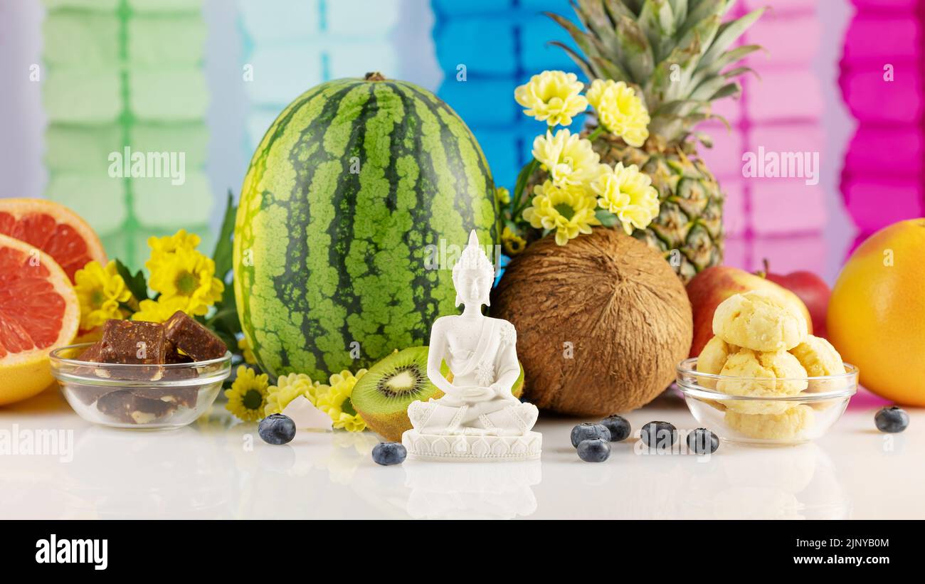 Vesak, Buddha Day. Buddha statue with offerings, fruits, sweets
