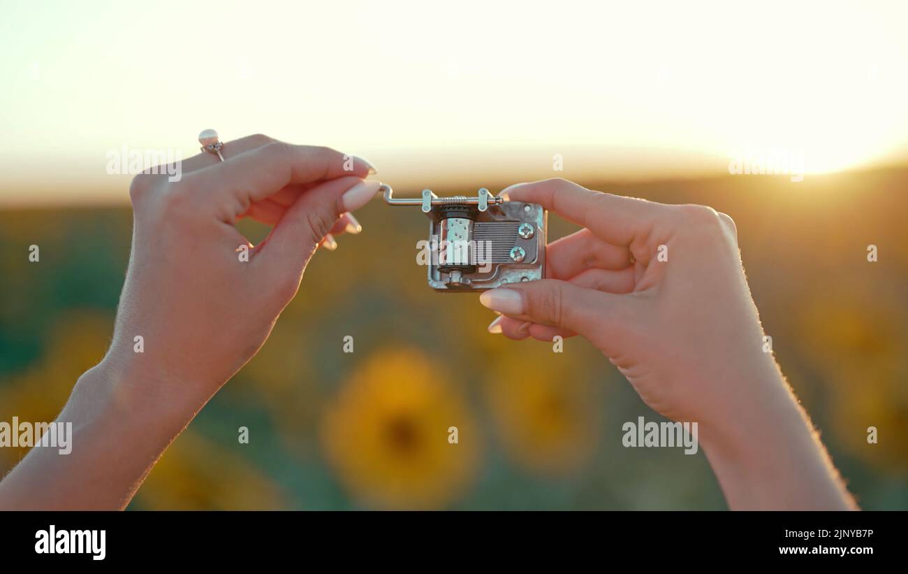 Female hands rotating gears of old music box mechanism. Lady turning