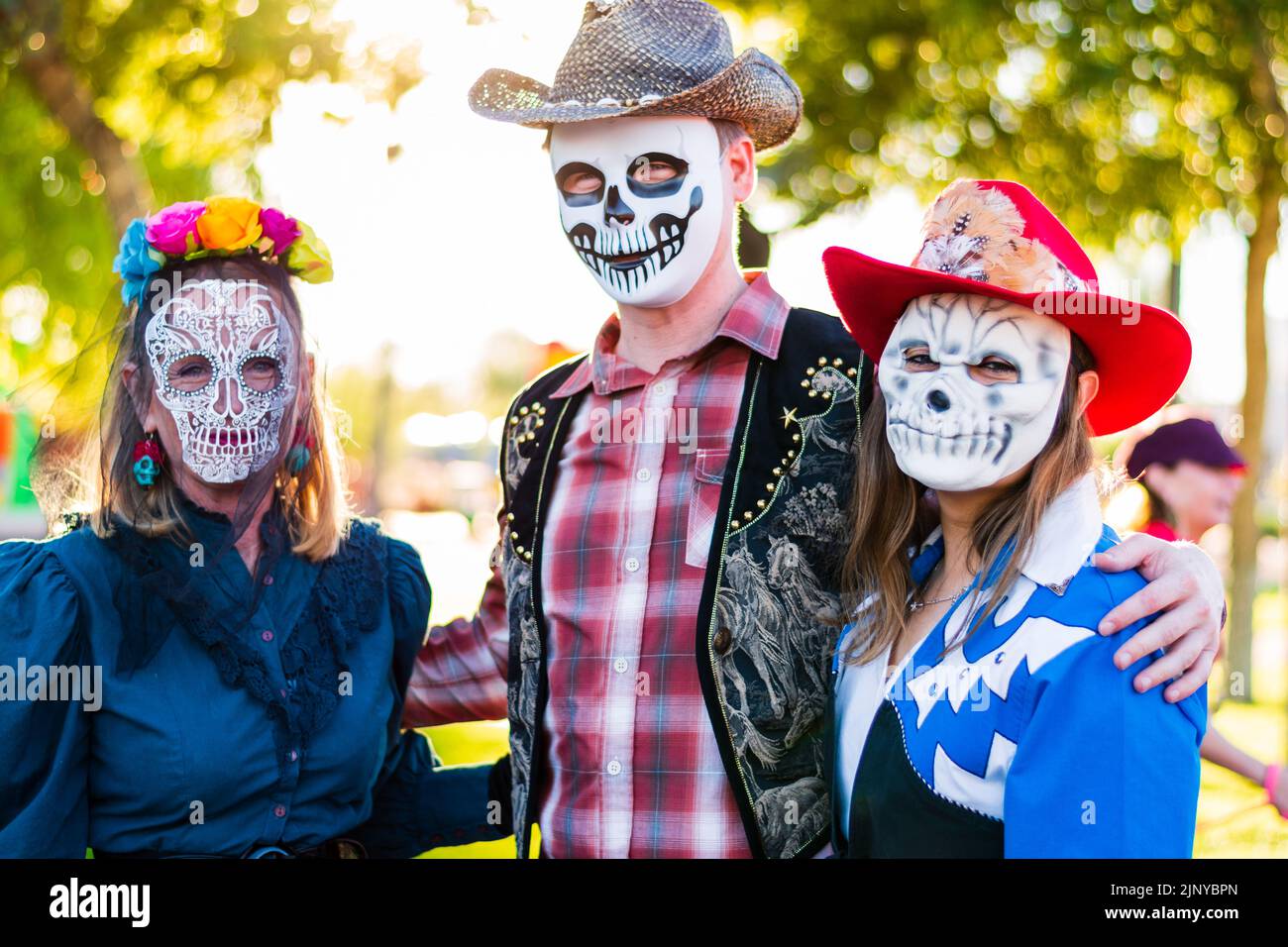 Family of three dressed in western style sugar skull halloween costumes