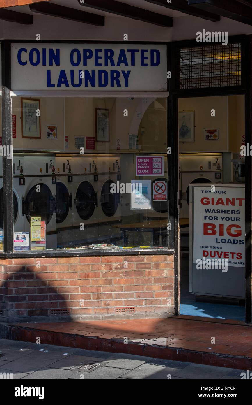 coin operated launderette or laundrymat with washing machines and tumble dryers, coin operated laundry shop for washing clothes, pay as you go. Stock Photo