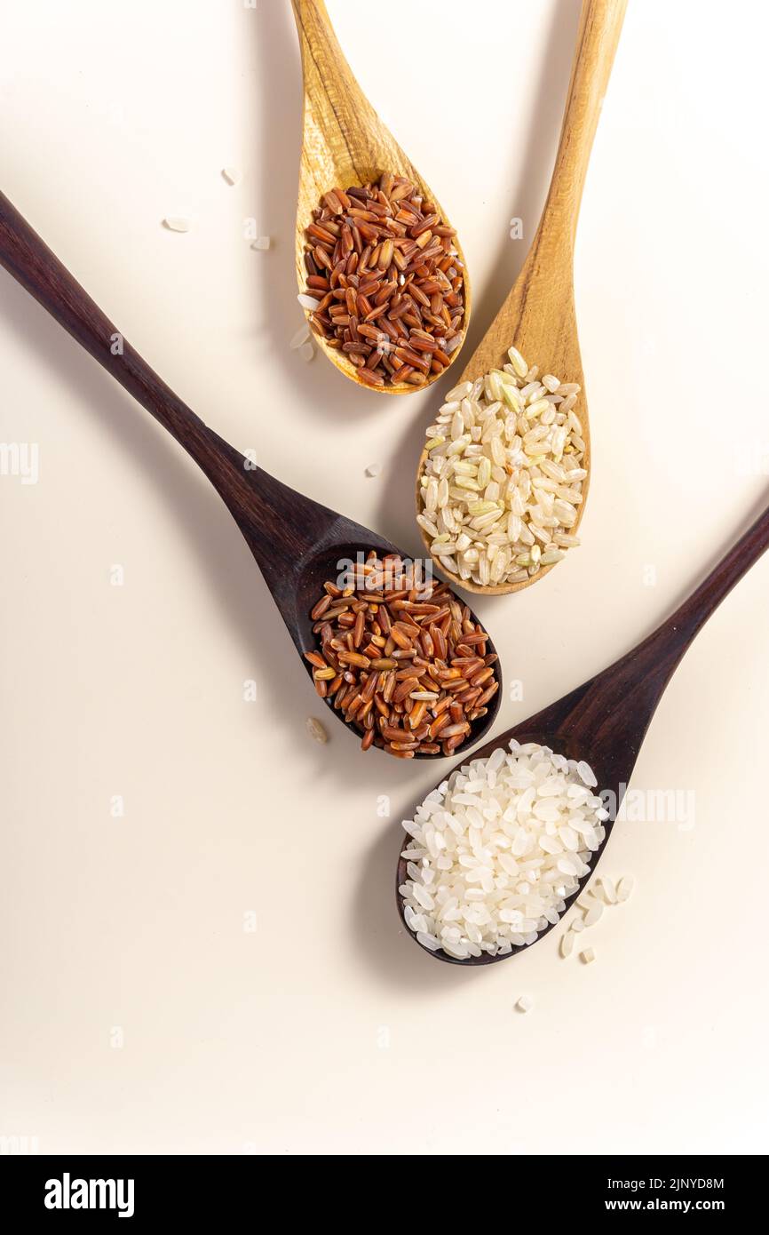 Assorted White Rice Raw and uncooked rice assortment in wooden spoon on white background ...