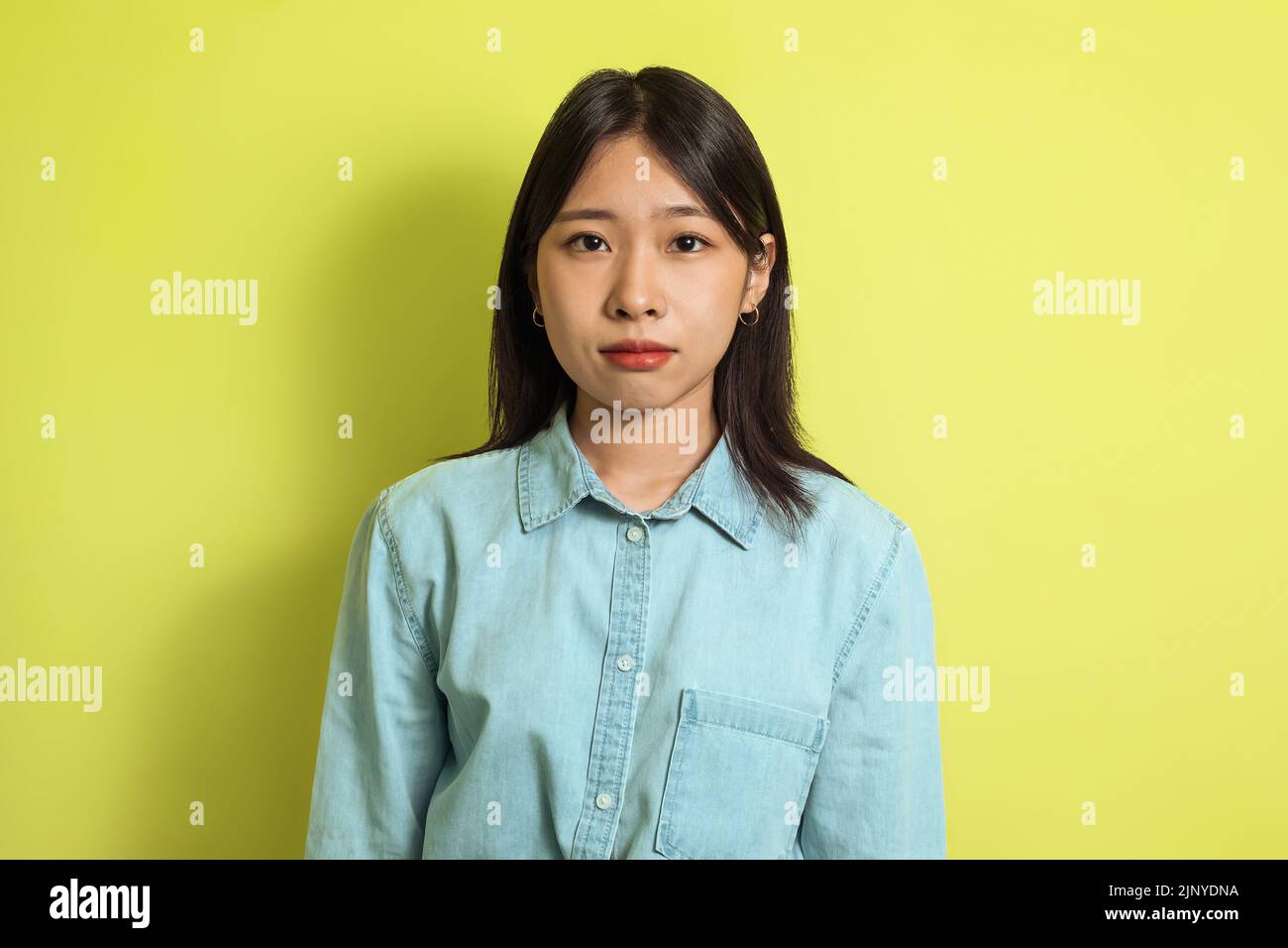 Portrait Of Serious Korean Woman Posing Standing Over Yellow Background Stock Photo