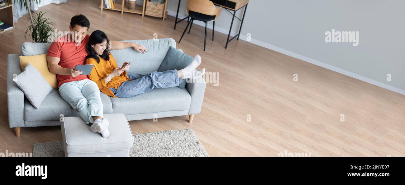Wide Extended Banner With Happy Asian Couple Relaxing Together At Home Stock Photo