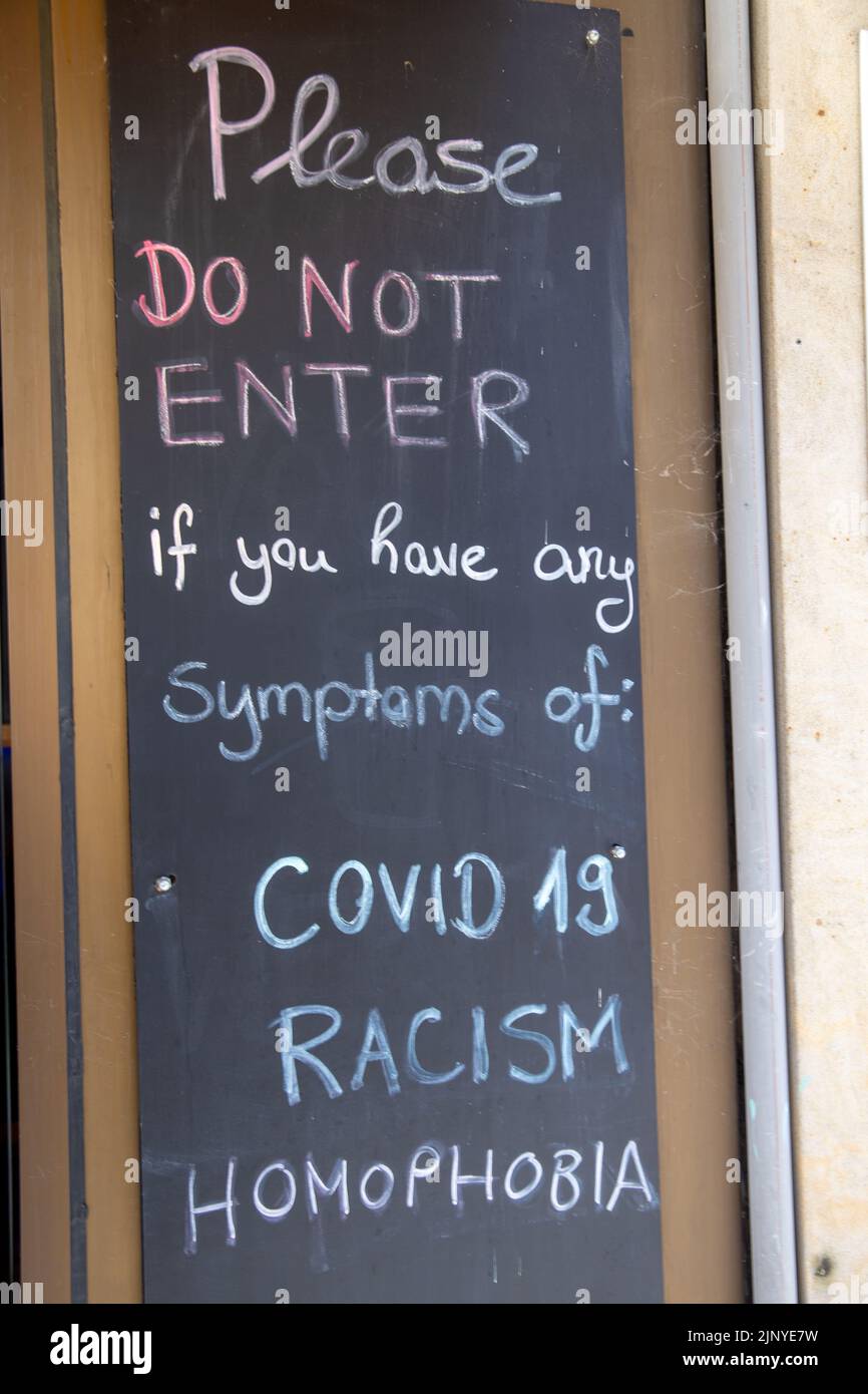 Display in front of a pub in Germany: Guests are informed in English that they are not welcome if they have symptoms of Corona, racism and homophobia Stock Photo