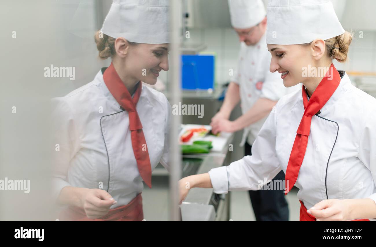 Chefs in large commercial kitchen cooking meals together Stock Photo