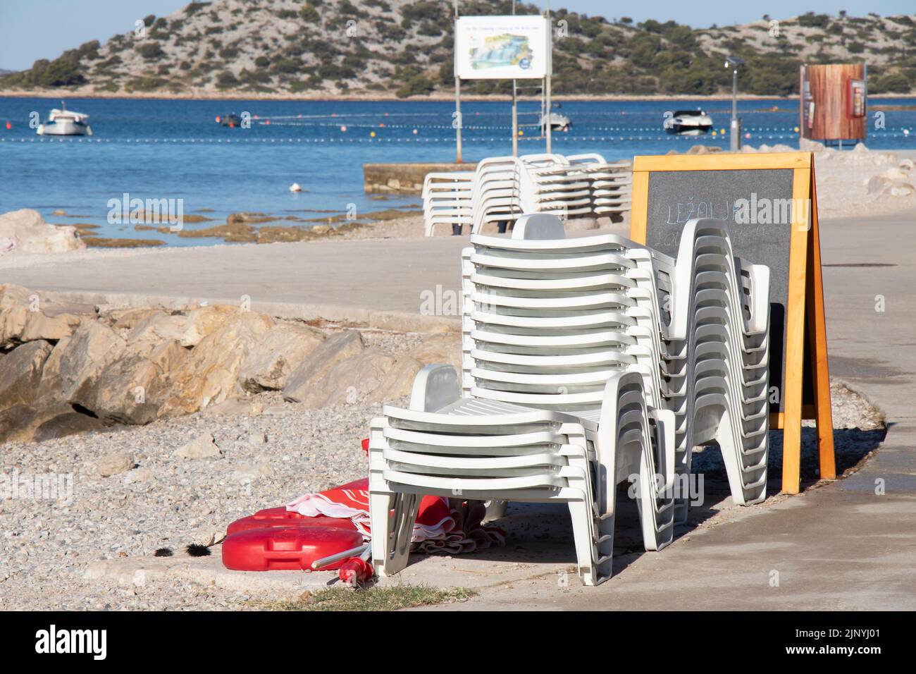 Vodice, Croatia - July 13, 2022: Plastic sun beds and parasols on an empty beach in Croatia Stock Photo