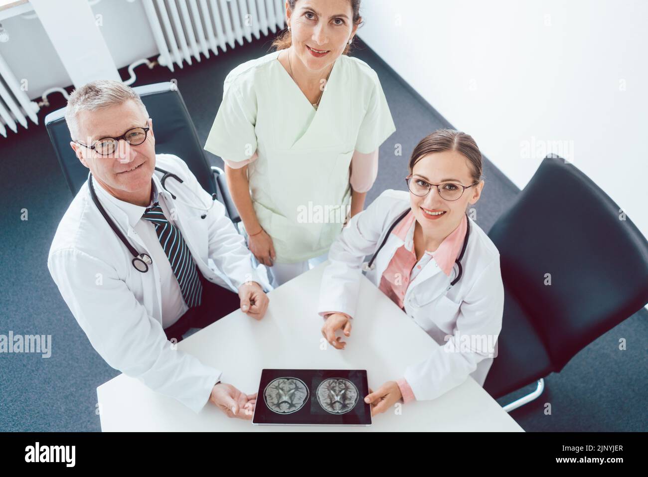 Team of doctors and nurses in meeting using a tablet computer Stock Photo