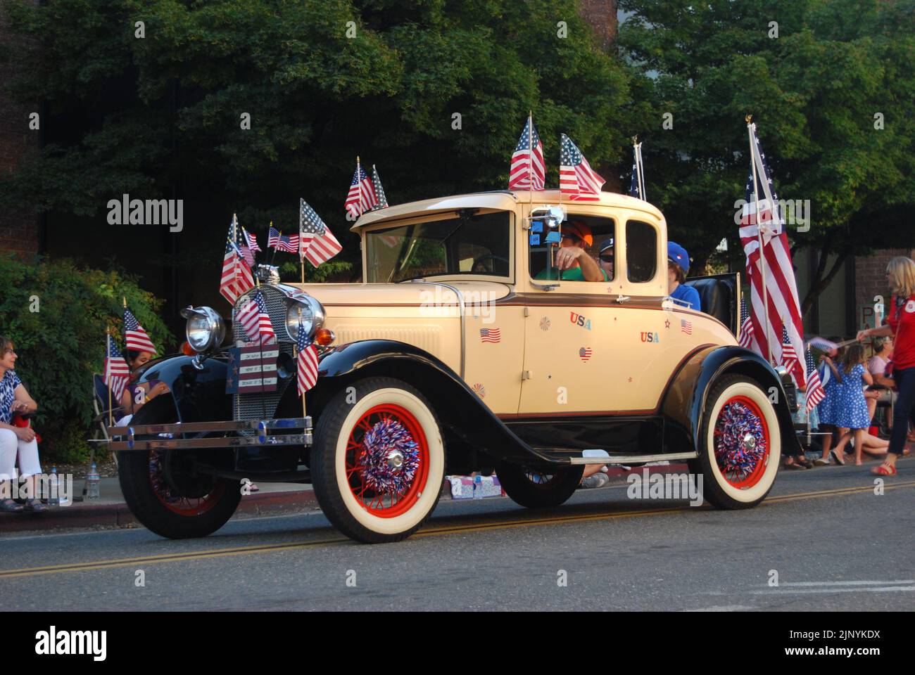 A 1930 Ford Model A Rumble Seat Coupe decorated with Stars & Stripes flags in an Independence Day 4th July parade in Auburn, CA. Stock Photo