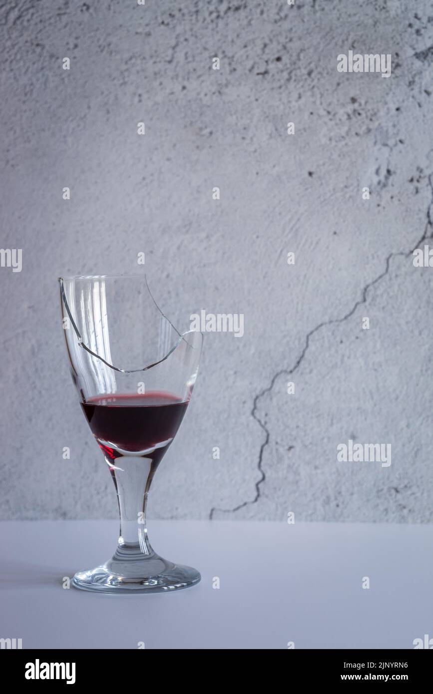 Broken, shattered wine glass quarter filled with red wine - studio shot Stock Photo