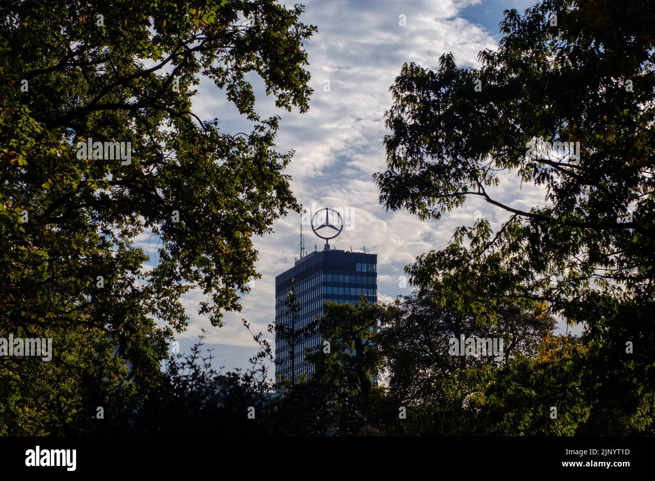 Mercedes Benz star on top of the Europacenter tower seen through dark branches in Berlin, Germany in October 2018. Stock Photo
