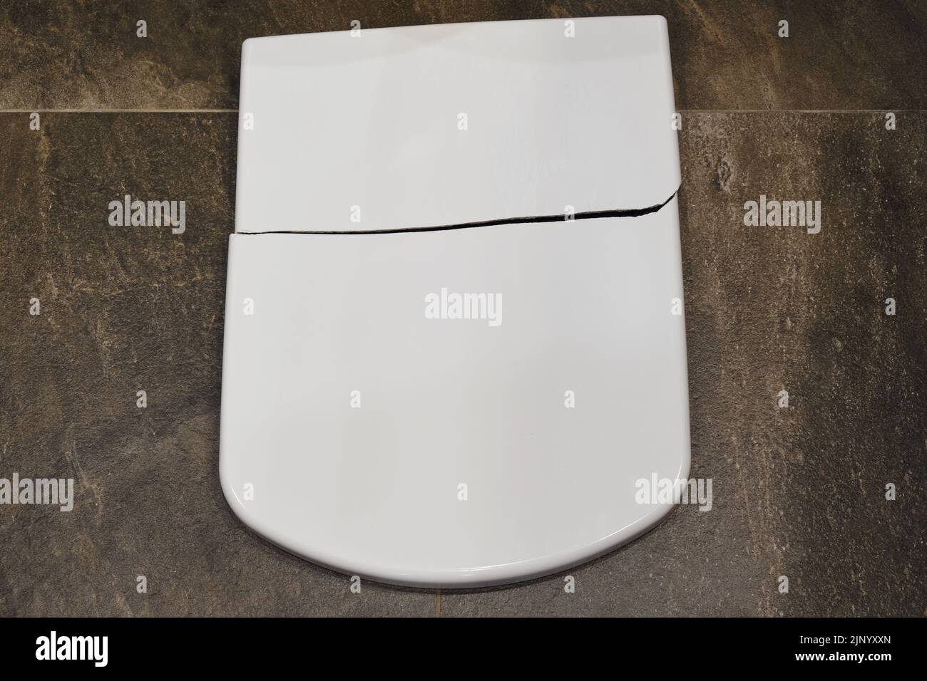 Cracked white toilet lid. A broken closing lid in the home toilet Stock