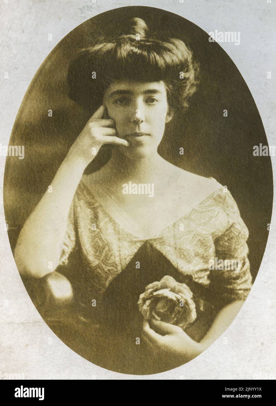 Vintage studio photograph of young woman taken in the early 20th century She is making a hand gesture that looks like Call Me This closeup portrait is circa 1900 Stock Photo