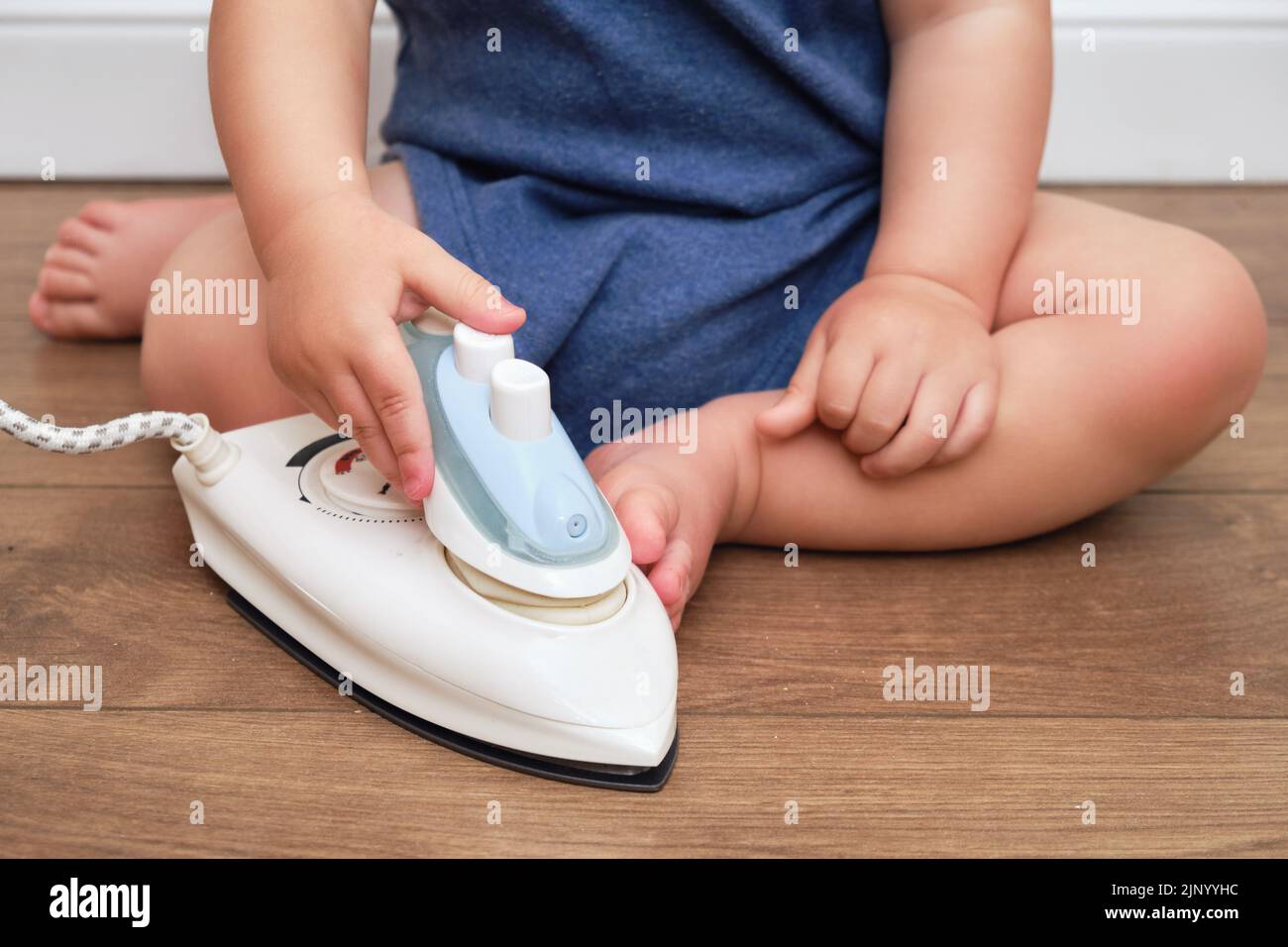 Toddler baby plays with a hot electrical iron. Child boy holding a