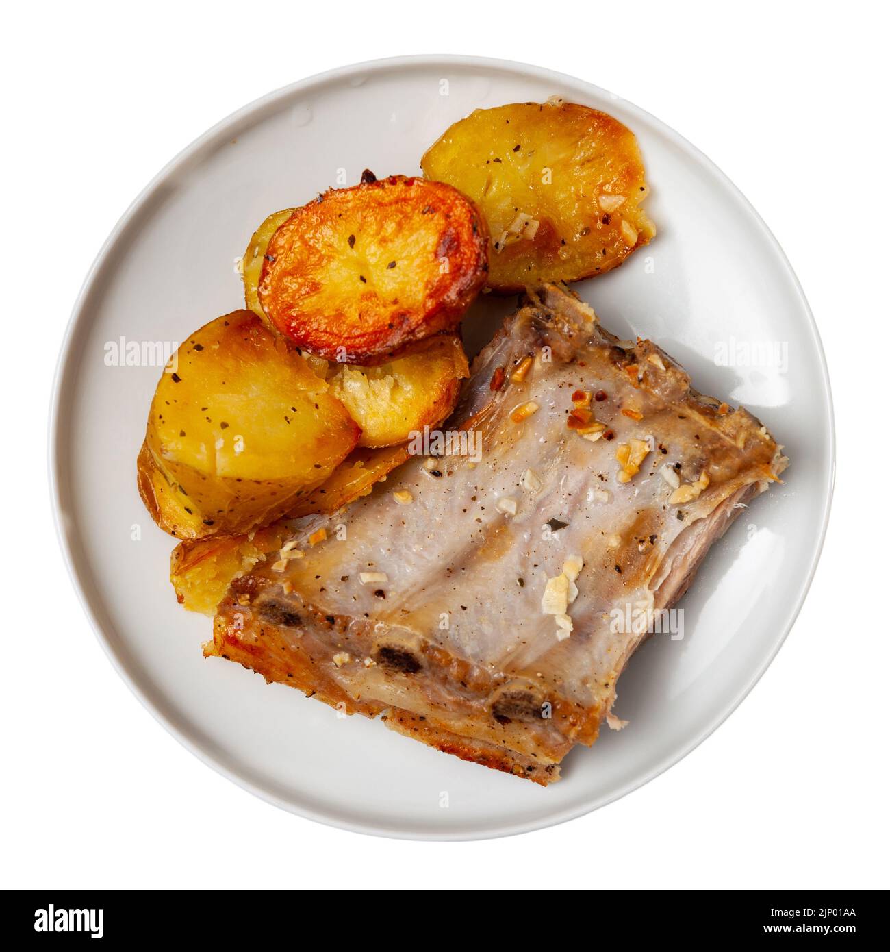 Pork ribs with boiled potatoes and spices on ceramic plate Stock Photo