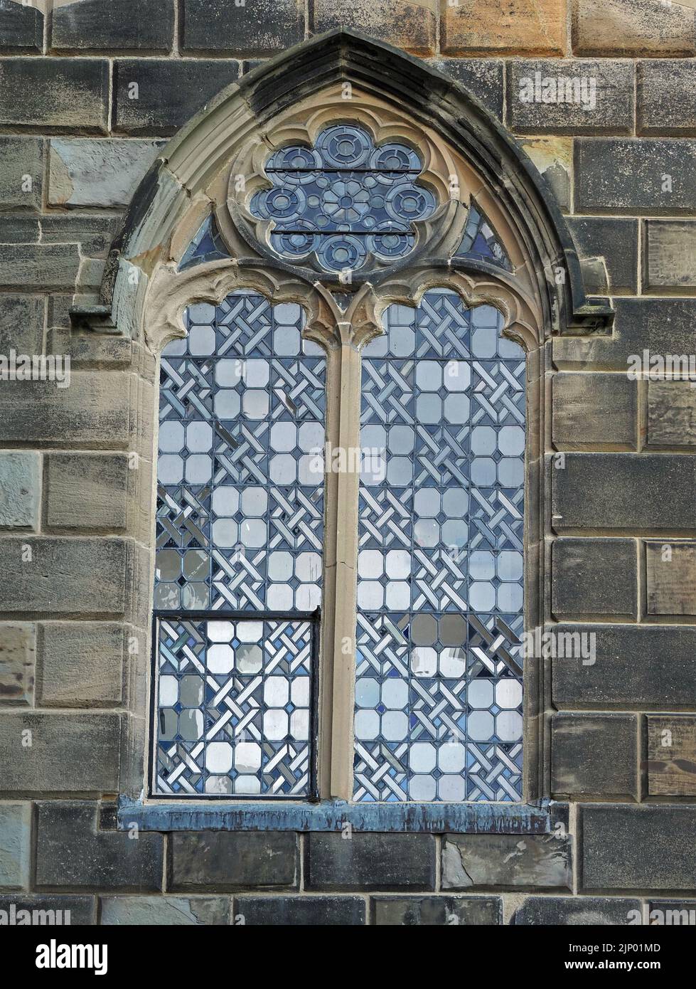 contrasting patterns in ancient glass of arched mullion window above stonework entrance to Bishop's Palace, Bishop Auckland, County Durham, England UK Stock Photo