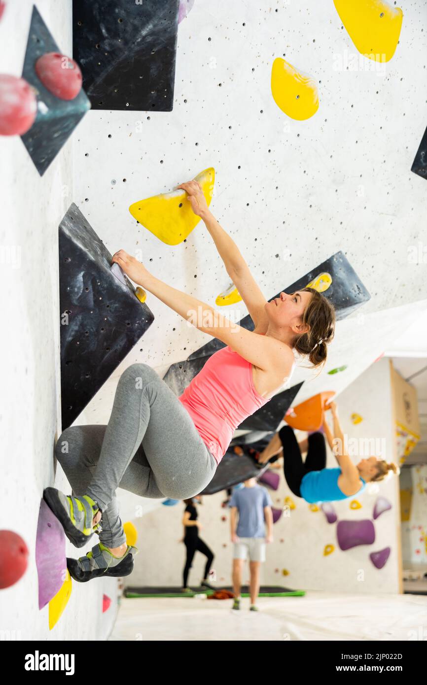 Young female alpinist practicing indoor rockclimbing on a artificial