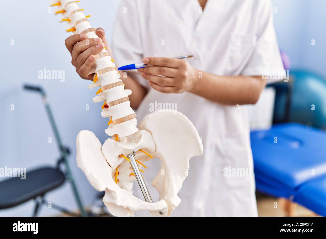Young latin woman wearing physiotherapist uniform pointing to