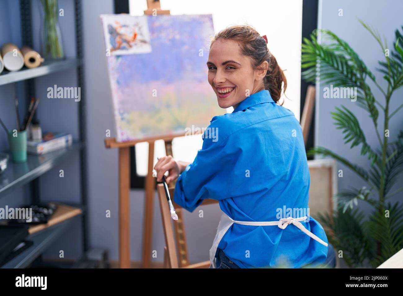 Young woman artist smiling confident sitting on chair at art studio ...