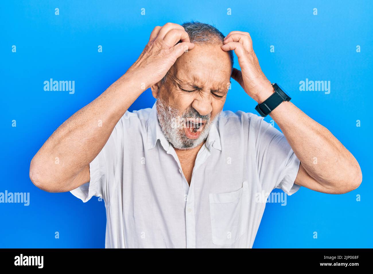Handsome senior man with beard wearing casual white shirt suffering ...