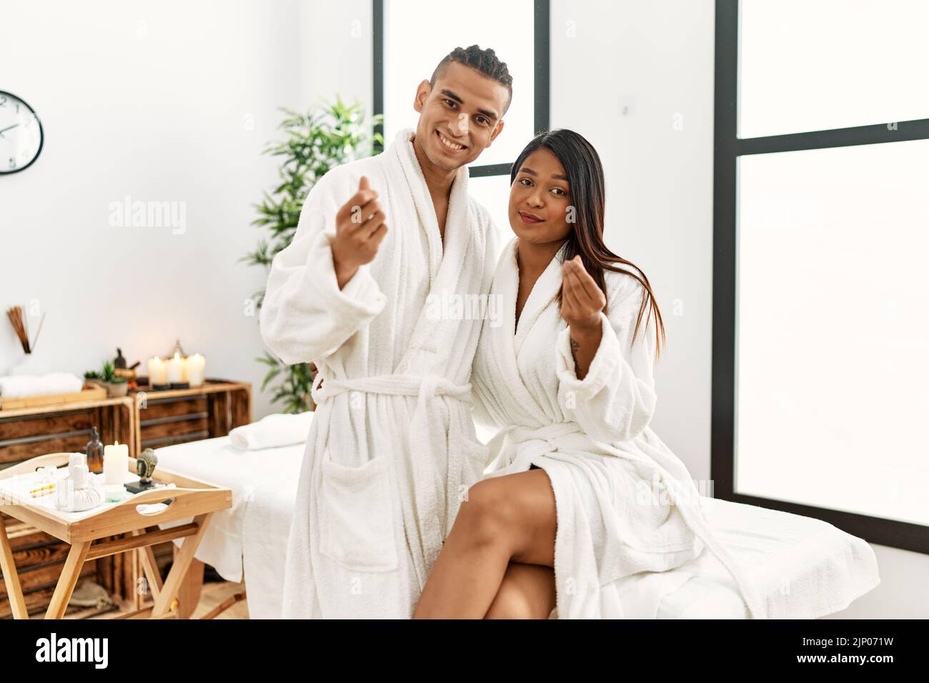 Young latin couple wearing towel standing at beauty center doing money