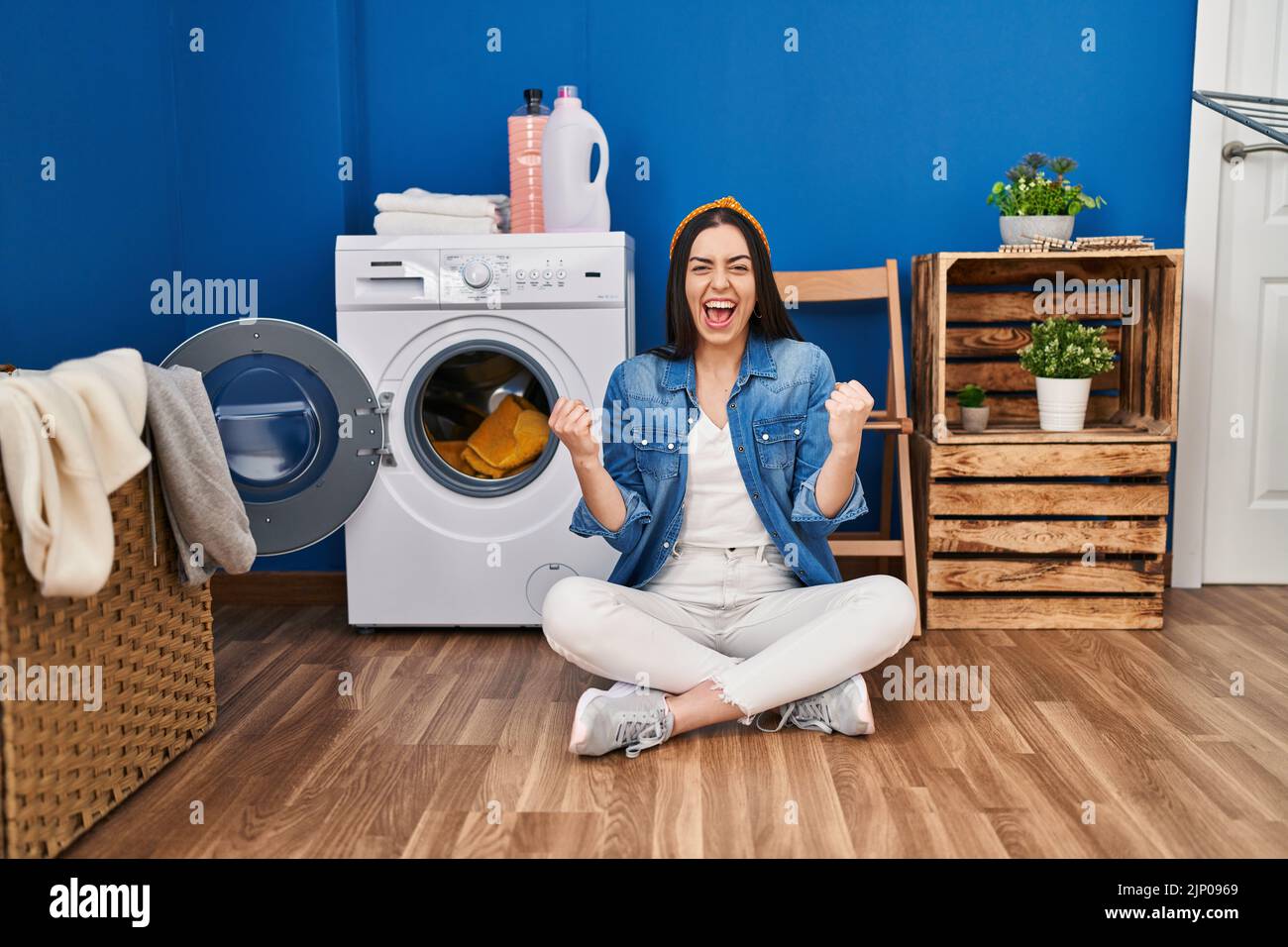 Hispanic woman doing laundry sitting on the floor very happy and ...