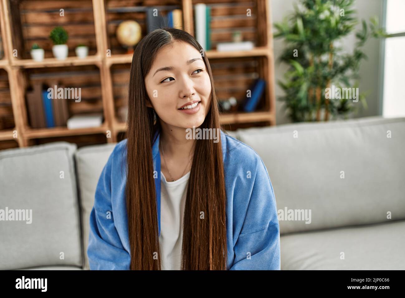 Young chinese girl smiling happy sitting on the sofa at home Stock ...