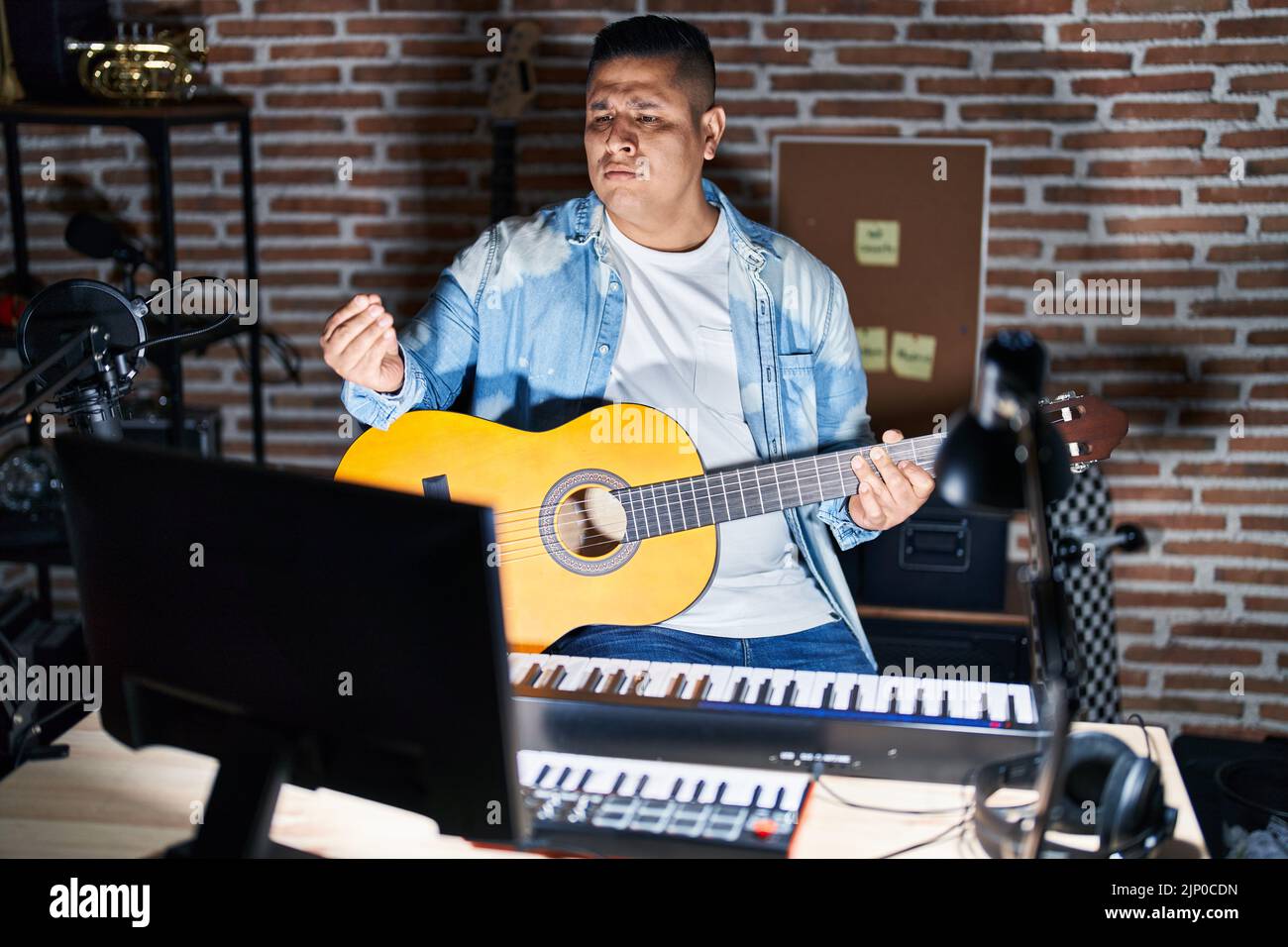 Hispanic young man playing classic guitar at music studio doing money