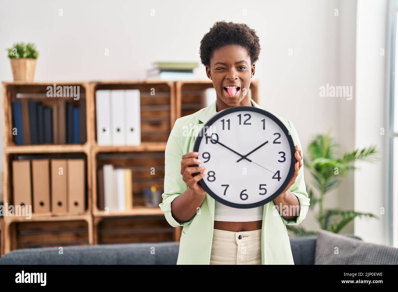 Comically Big Clock African american woman holding big clock sticking tongue out happy with ...