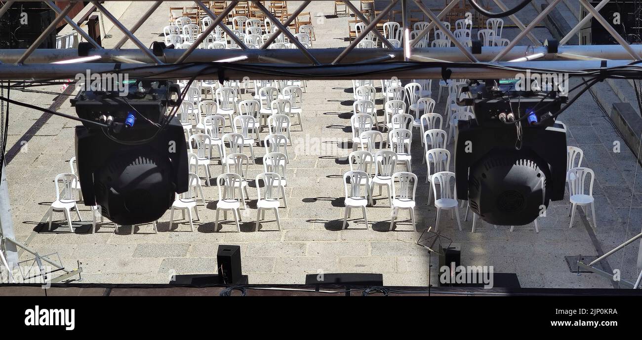 Spot lights structure over white plastic chairs for audience. Summer concerts in the city concept Stock Photo