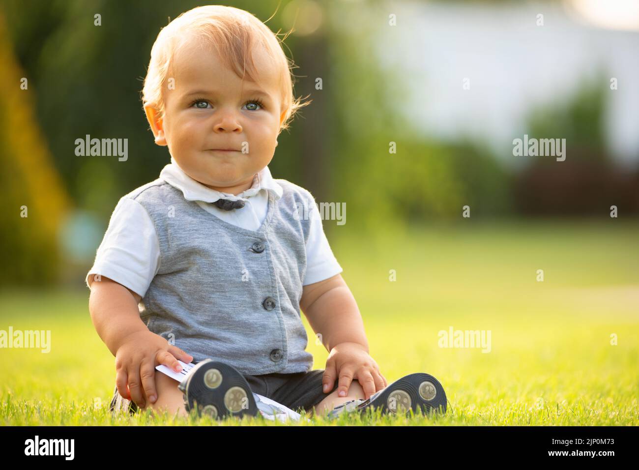 A cheerful baby is sitting on the lawn Stock Photo - Alamy