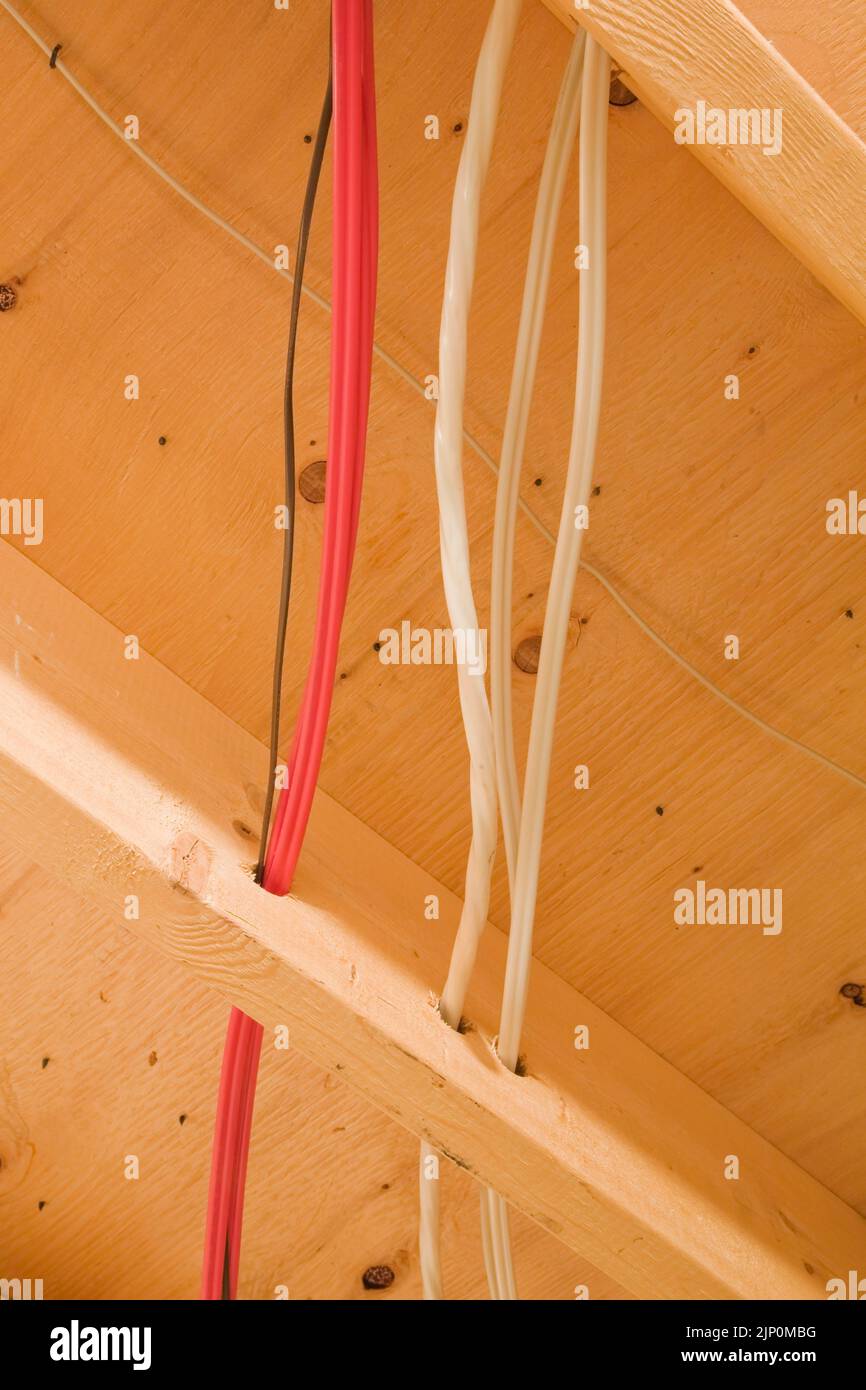 Closeup of electrical wiring passing through the holes drilled in the floor jost inside home