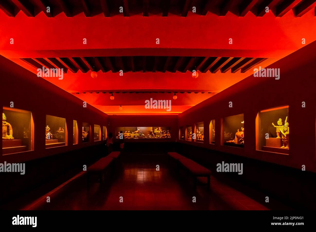 room with red light, you can see a display of antique, primitive, or stone antiques Stock Photo