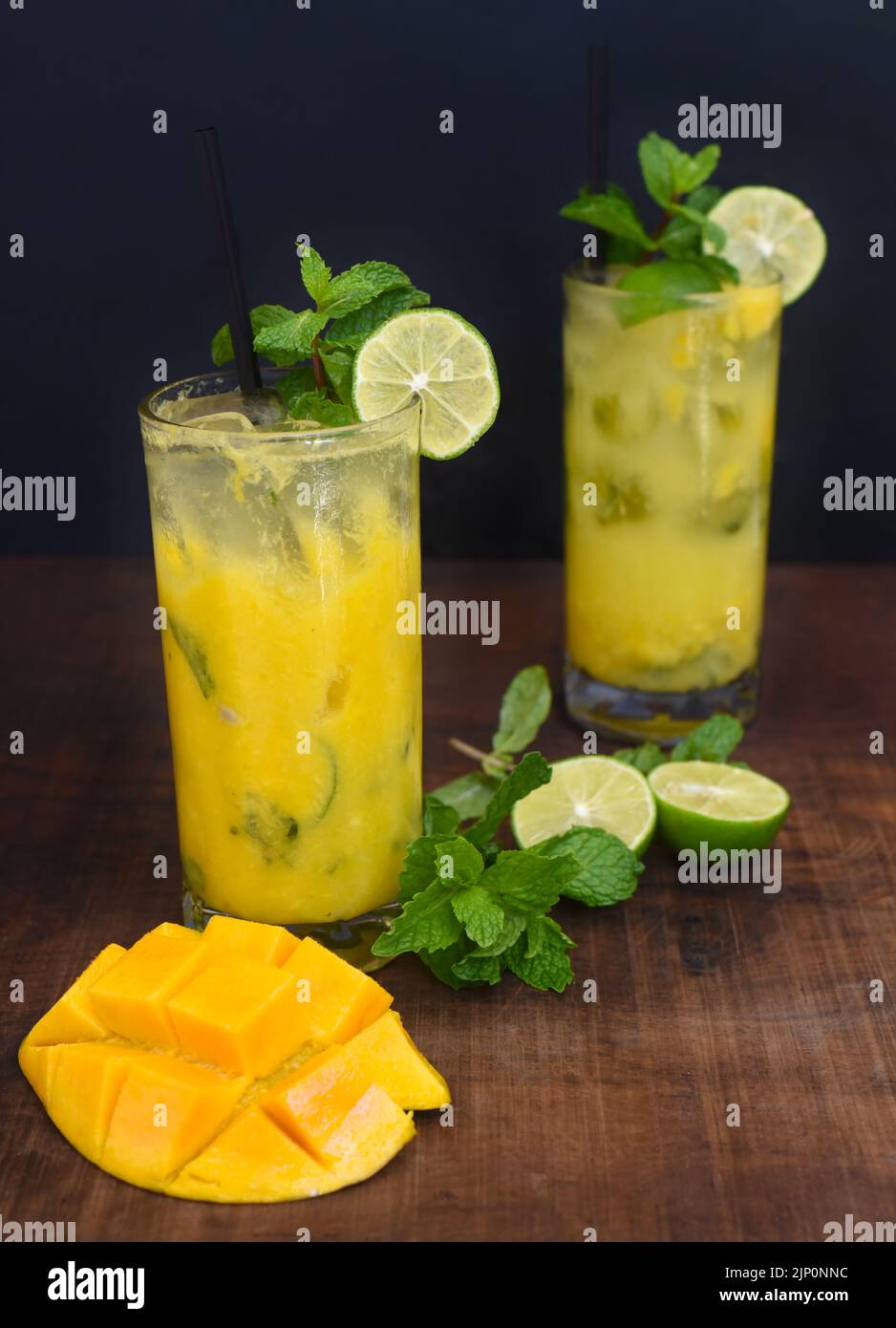 Highball glasses with mango mojito on wooden table and black background