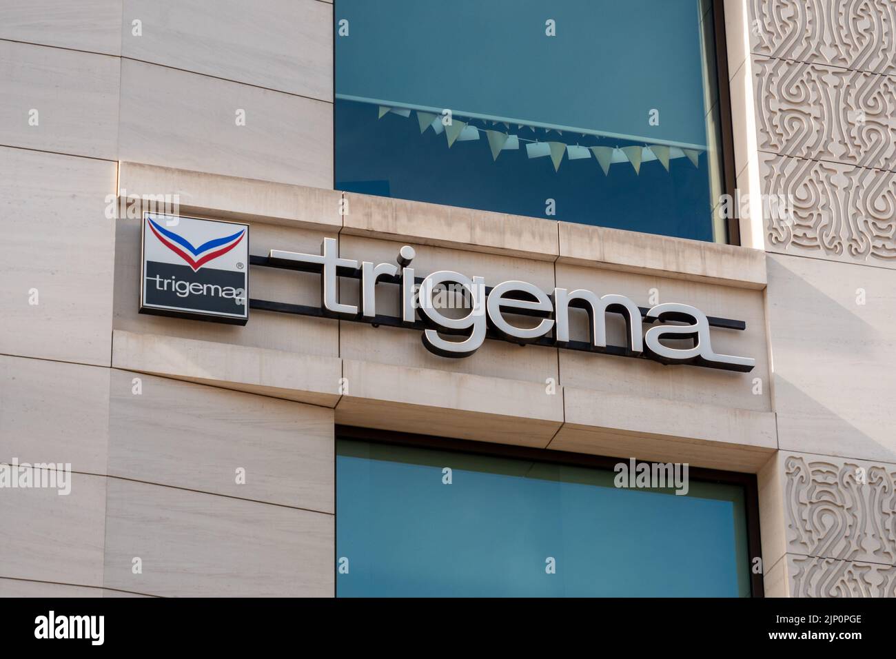 Trigema brand logo on a shopping mall exterior. Fashion label which produces the clothing in Germany. Quality textiles from a traditional company. Stock Photo