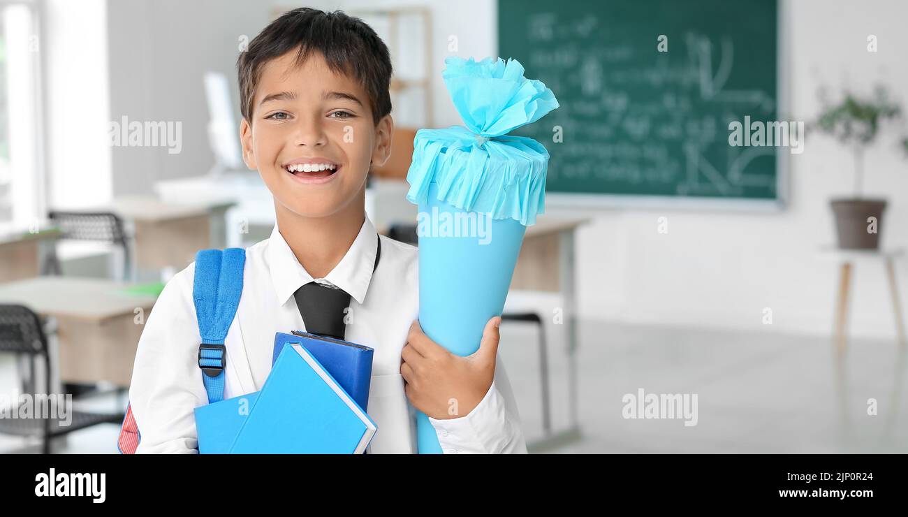 Cute little boy with school cone and books in classroom Stock Photo - Alamy