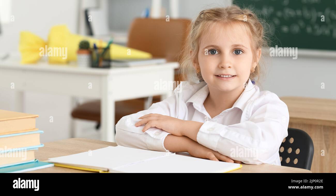 Cute little school girl sitting at desk in classroom Stock Photo - Alamy