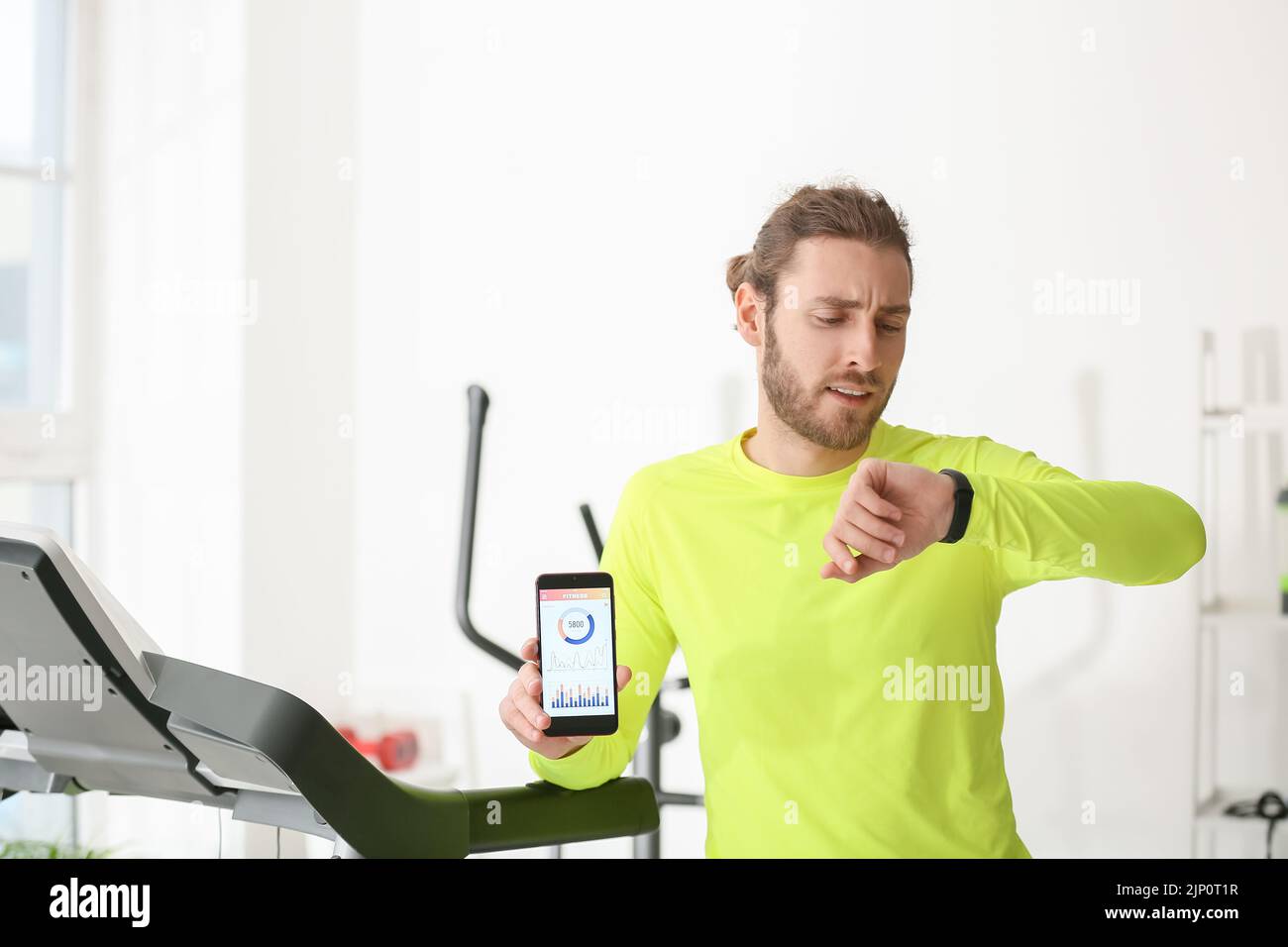 Sporty young man using phone with installed app for calories counting in gym Stock Photo