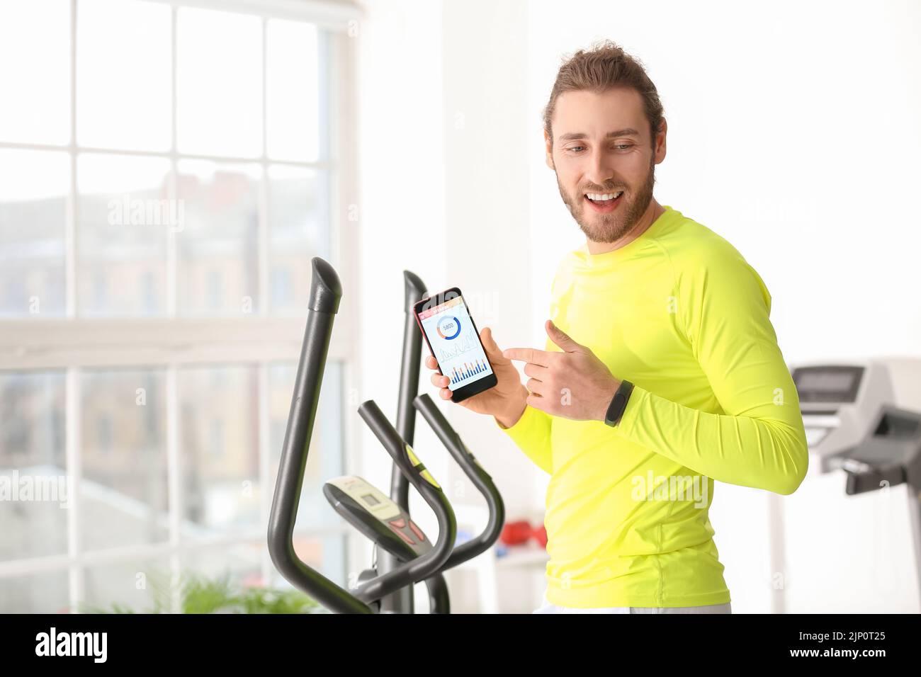 Sporty young man using phone with installed app for calories counting in gym Stock Photo