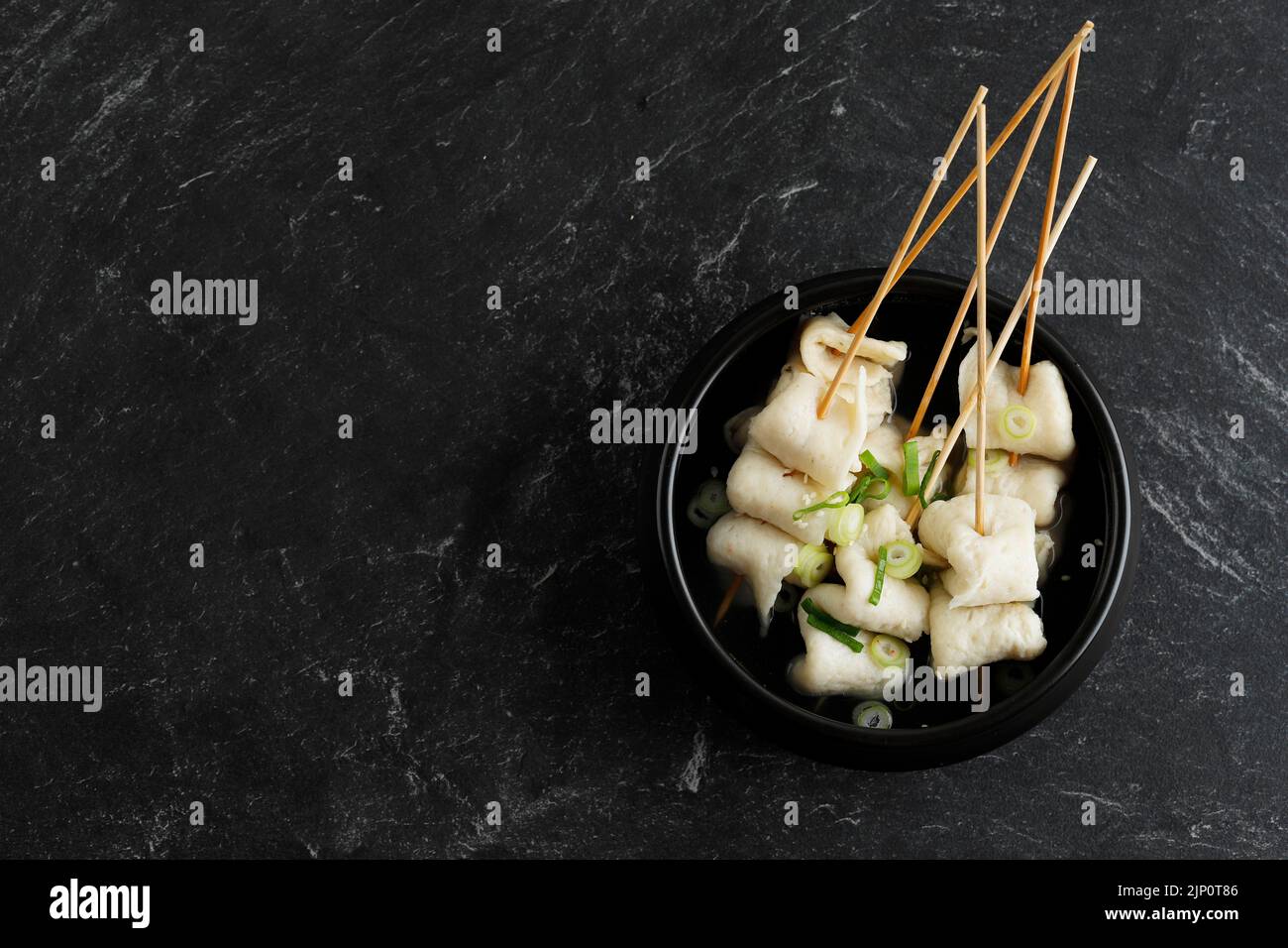 Odeng Oemuk Guk, Skewer Fish Cake Korean Popular Street Food Soup, Top View on Black Marble Table Stock Photo