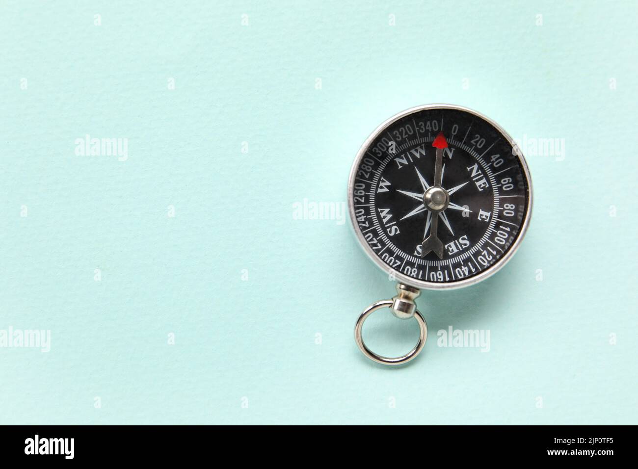 Tourist's compass on light blue background Stock Photo - Alamy