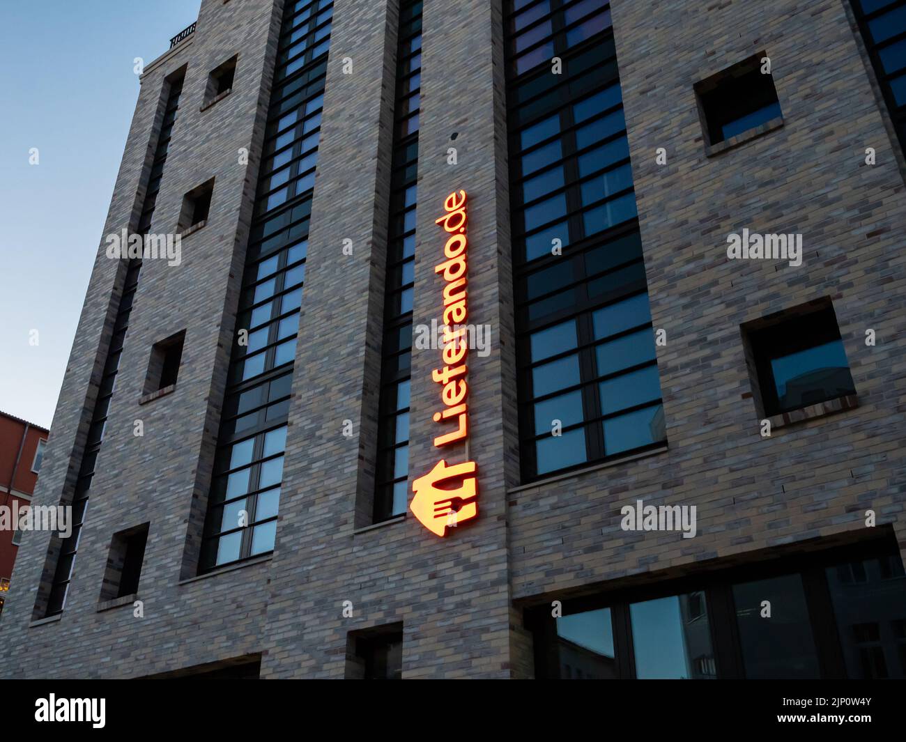 Lieferando logo on a building exterior. Illuminated sign of the food delivery service in the capital city. A brand of the company Just Eat Takeaway. Stock Photo