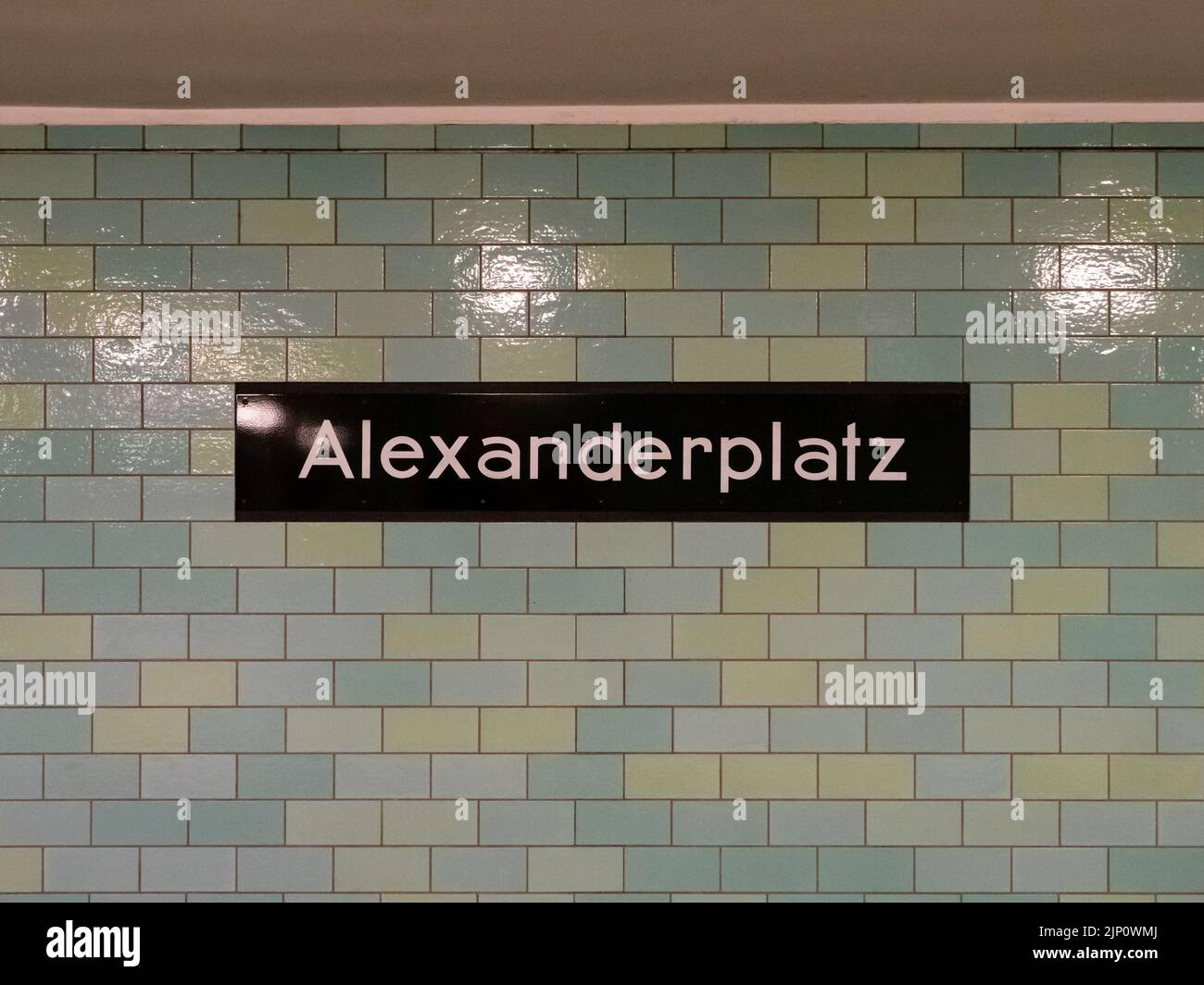 Alexanderplatz U-Bahn station in Berlin city. Name board with white letters on a black metal plate. The wall exterior is tiled in green color. Stock Photo
