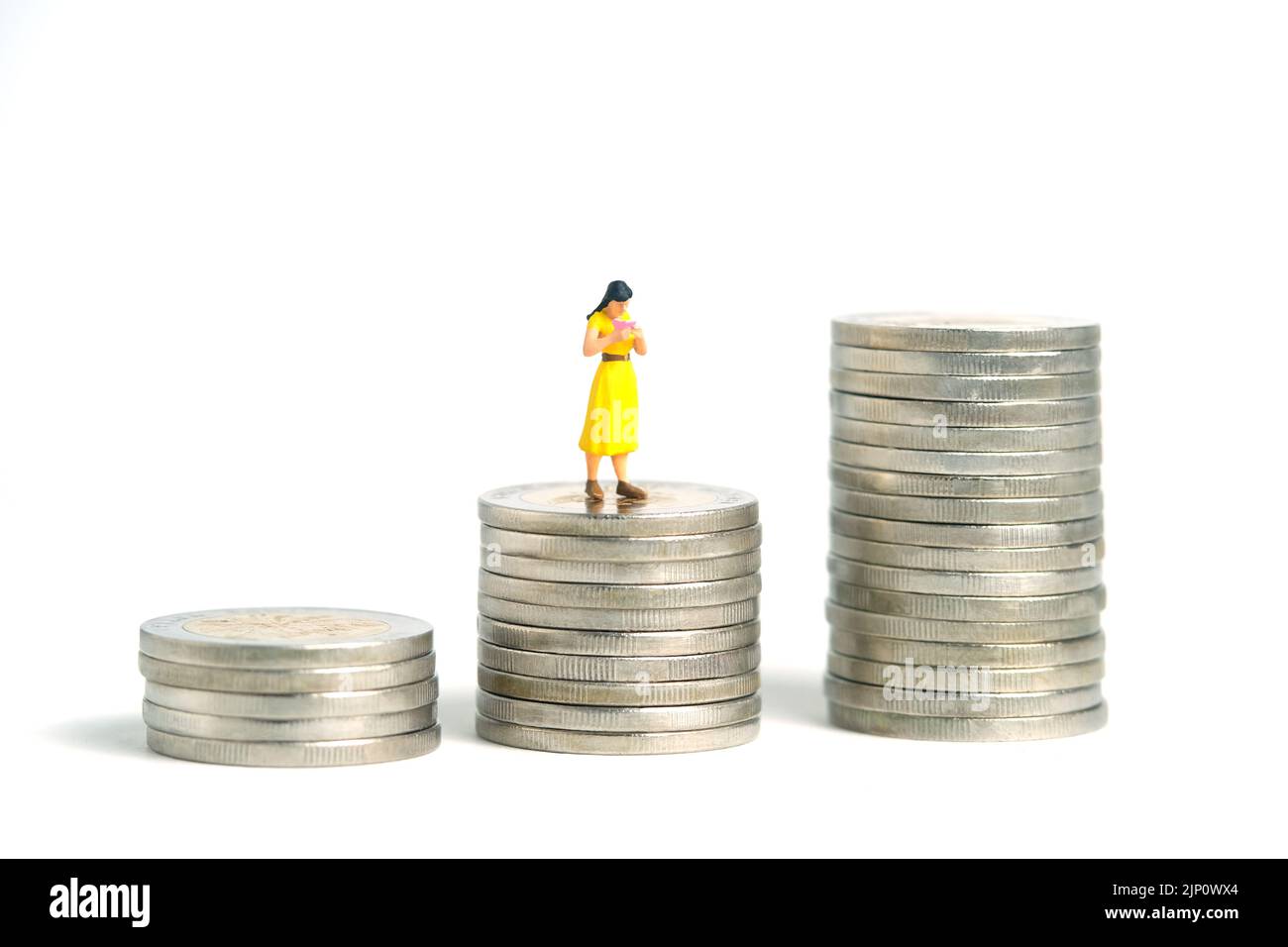Miniature people toy figure photography. A girl student standing above money coin stack, isolated on white background. Image photo Stock Photo