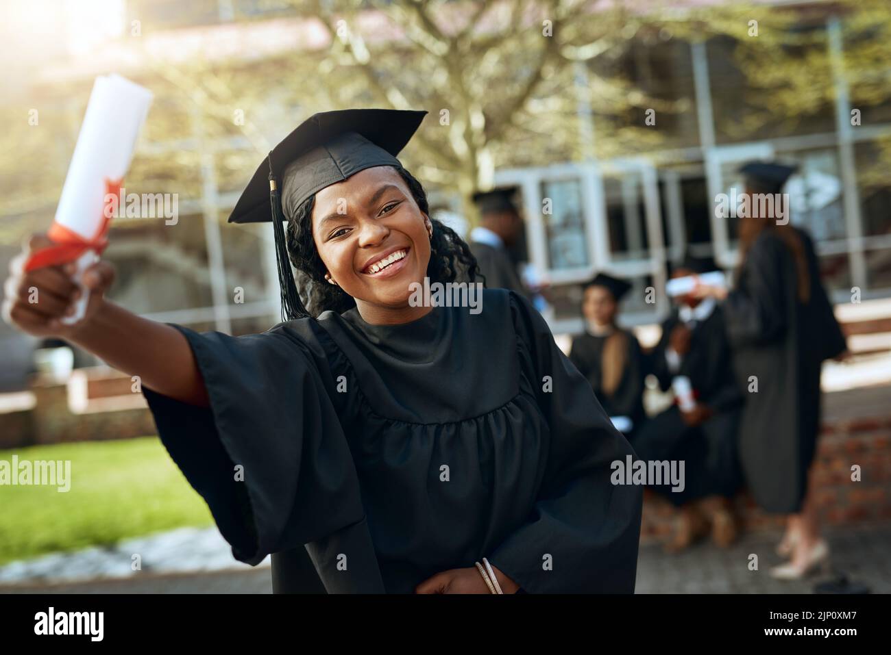 Im certified Hire me. Portrait of a happy young woman holding a diploma on graduation day. Stock Photo