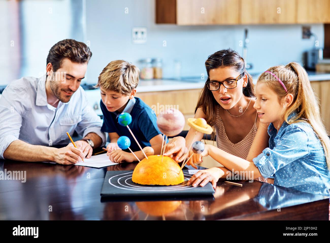 Learning through creativity. parents helping their kids with a school project at home. Stock Photo