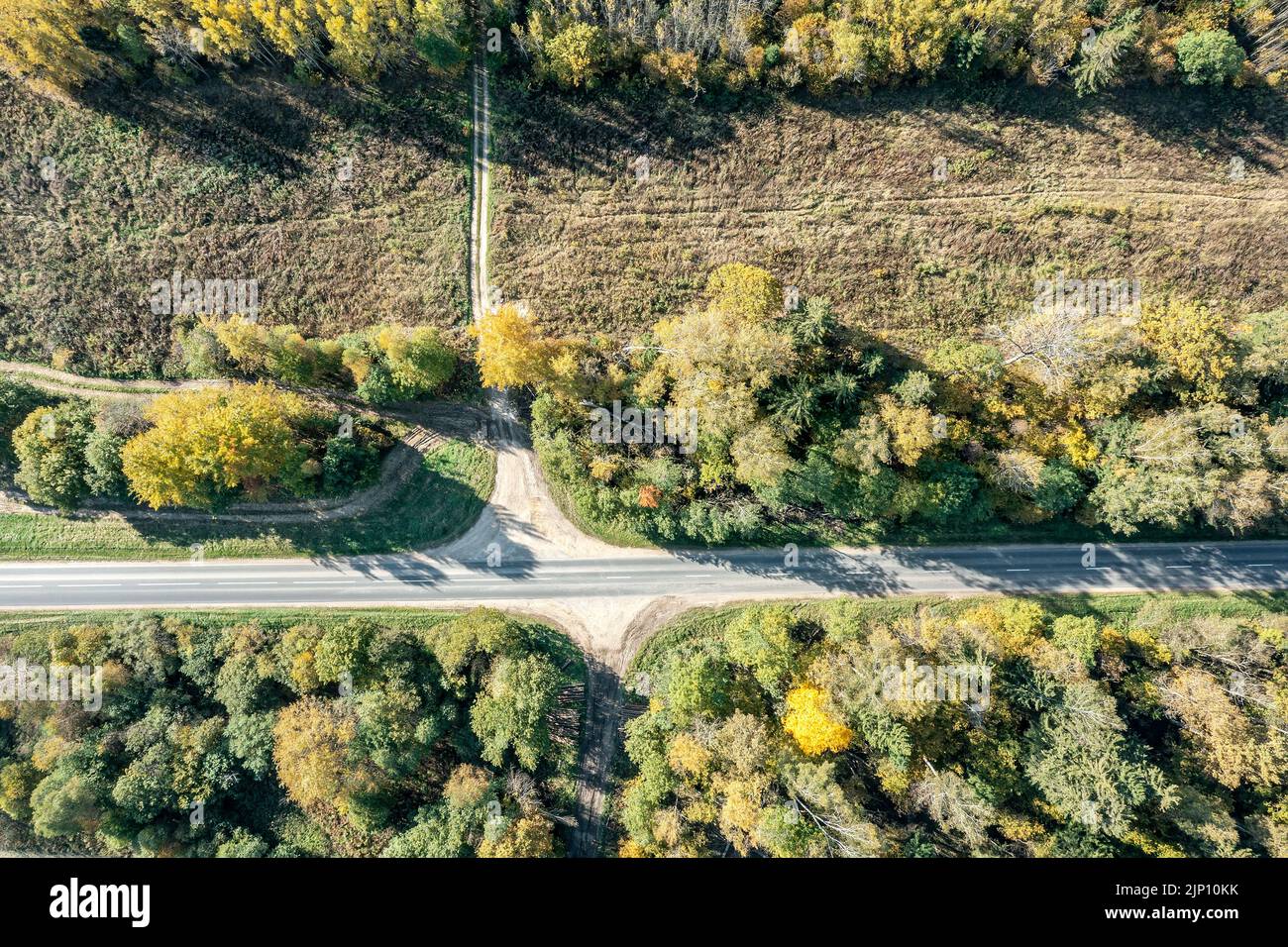 flying above rural road running through a scenic countryside. aerial top view on sunny day. Stock Photo