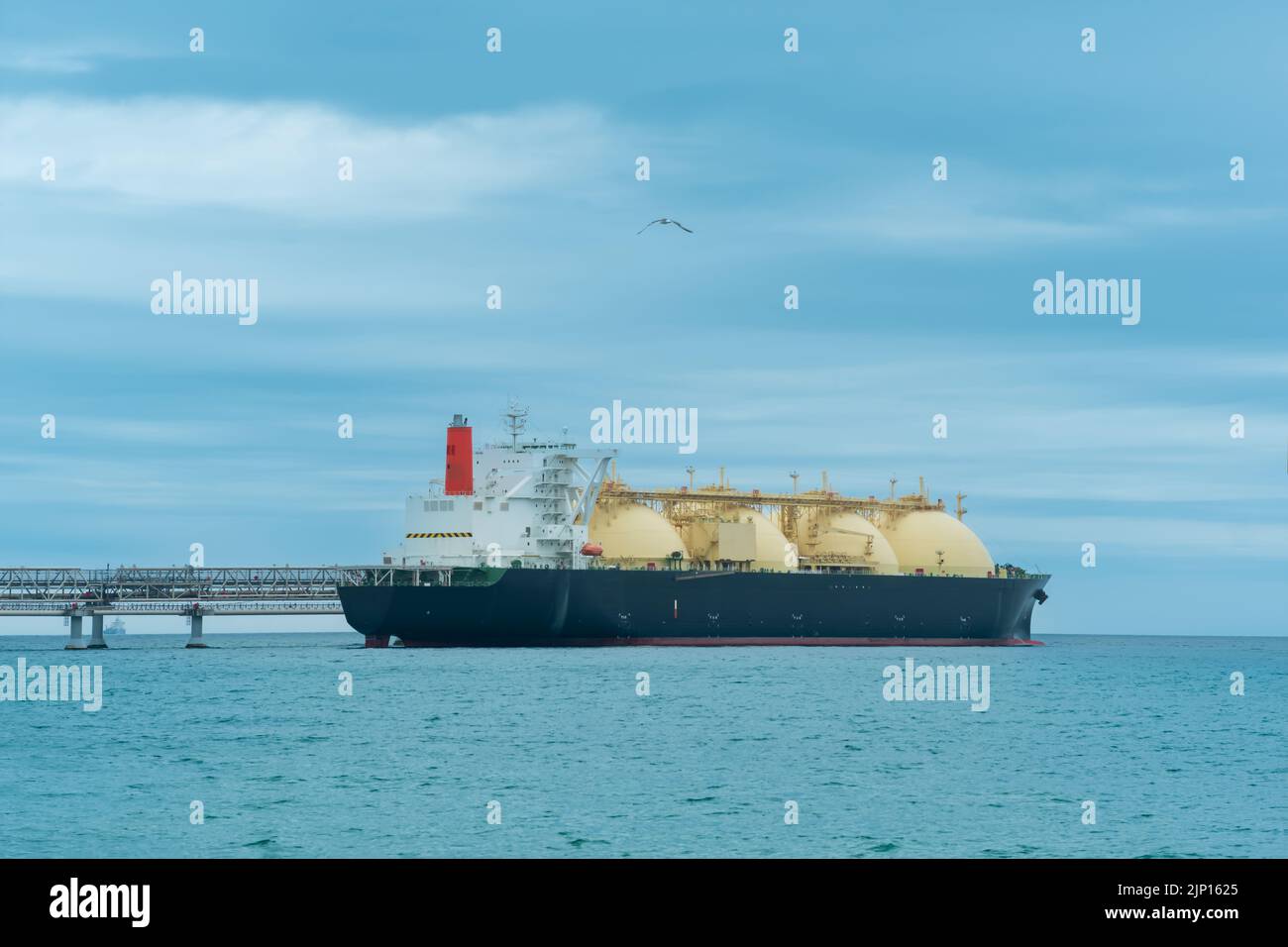 liquefied natural gas carrier tanker during loading at an LNG offshore terminal, in the distance